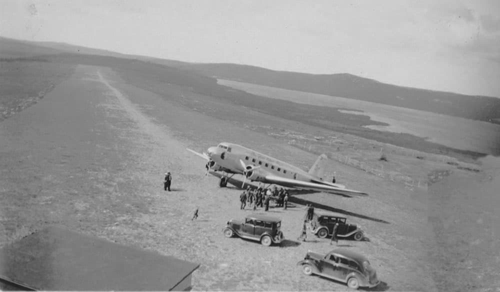 Early Canadian aviation - aircraft on a grass airstrip with vintage automobiles, circa 1930s
